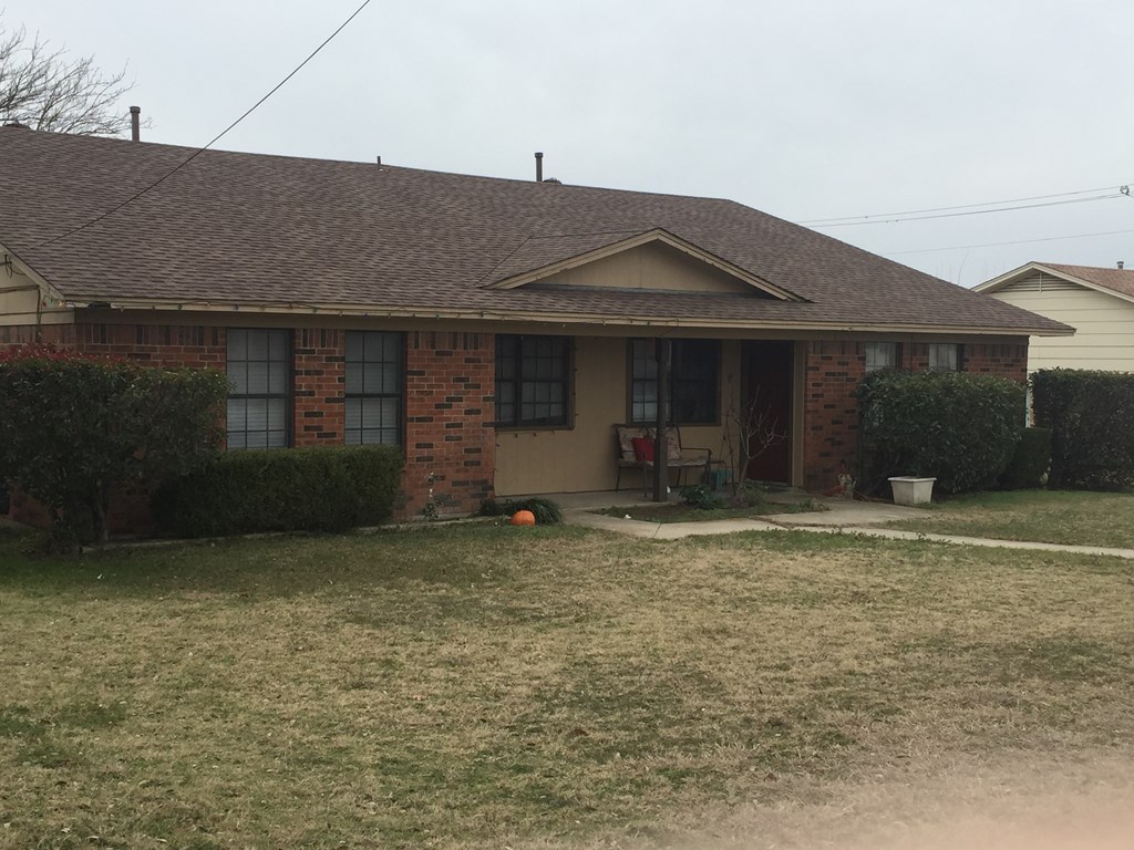 A house with a brown roof and a lawn in front.