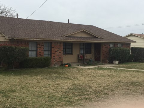 A house with a brown roof and a lawn in front.
