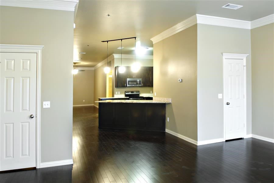 an empty kitchen and living room with a dark wood floor