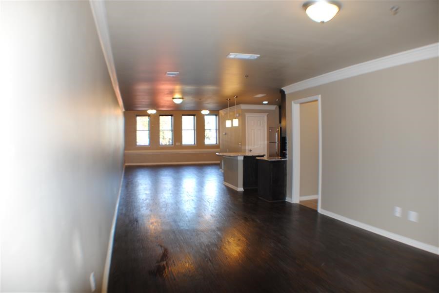 an empty living room and kitchen with wood floors