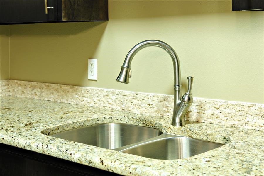 a kitchen sink with a faucet on a granite counter top