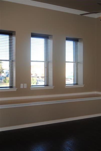 a living room with three windows and a dark floor