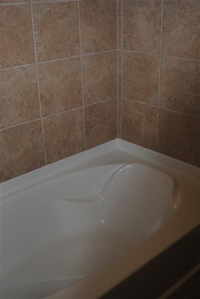 a white bath tub in a bathroom with tan tiles