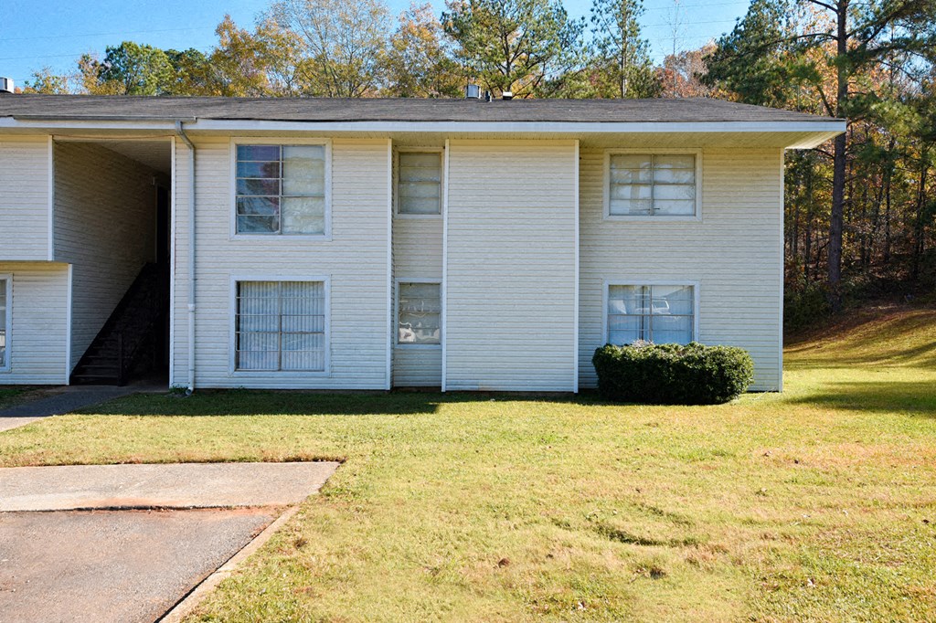 A white apartment building with a green lawn in front.