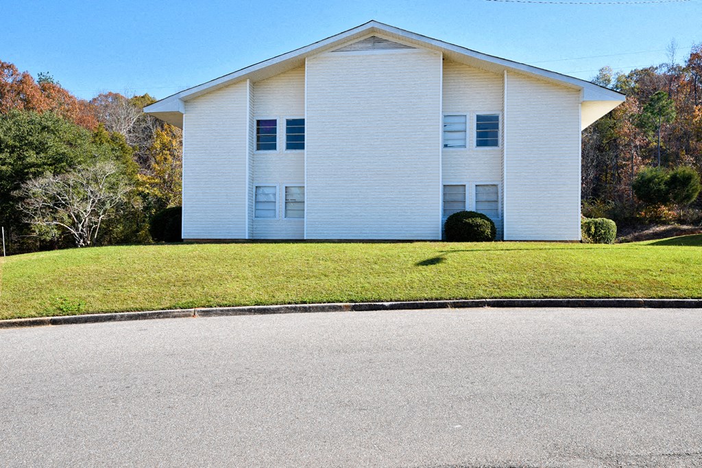 A white house with a grey roof and a green lawn in front.