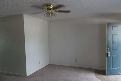 an empty room with a ceiling fan and a blue door