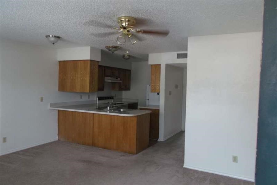 an empty room with a kitchen and a ceiling fan