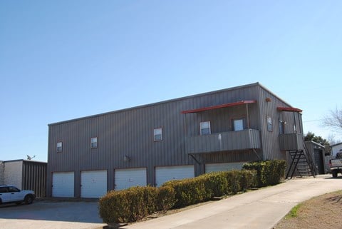 a large industrial building with three garage doors and a ladder