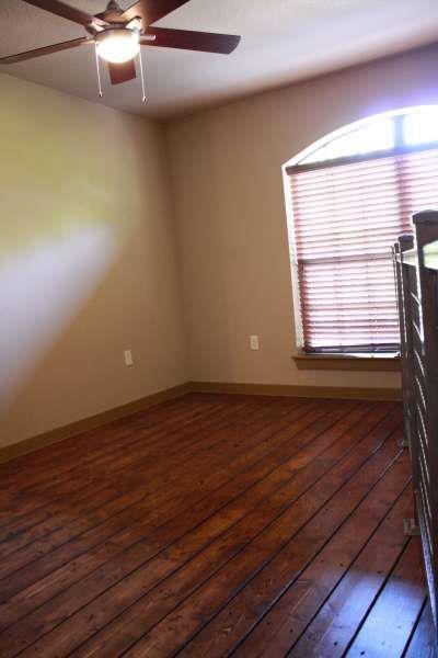 an empty room with a wooden floor and a ceiling fan