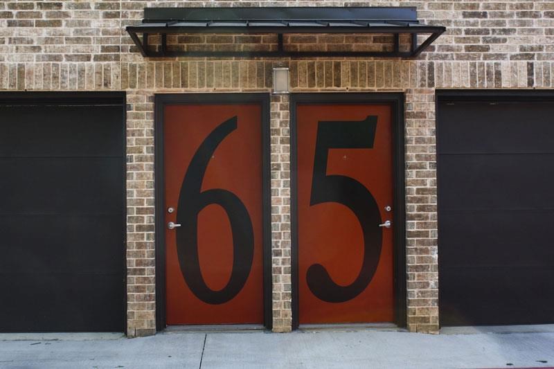 two red doors with the number 65 on a brick building