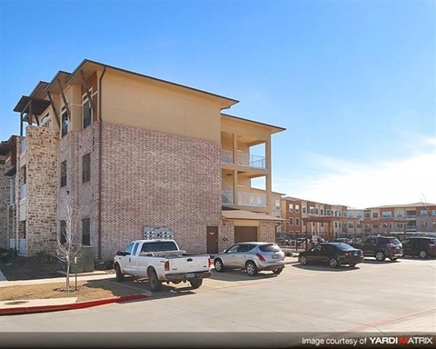 A white pickup truck is parked in front of a two-story apartment building.