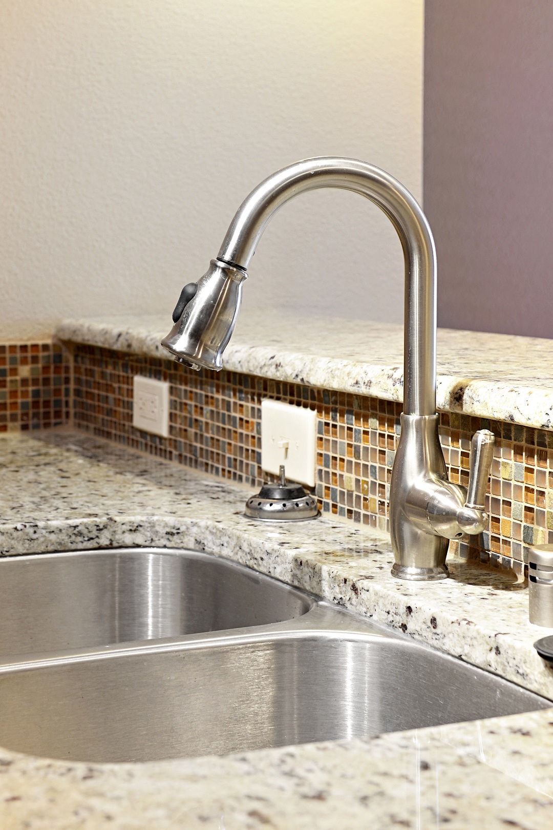 a kitchen sink with a chrome faucet and granite counter tops