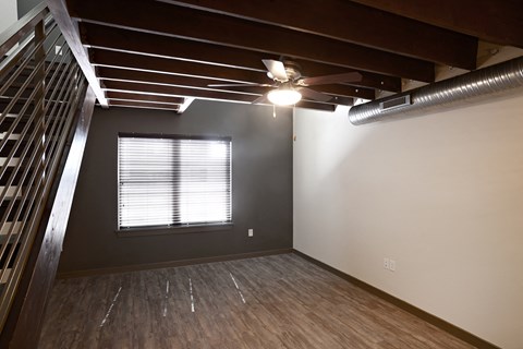 an empty living room with a ceiling fan and a window