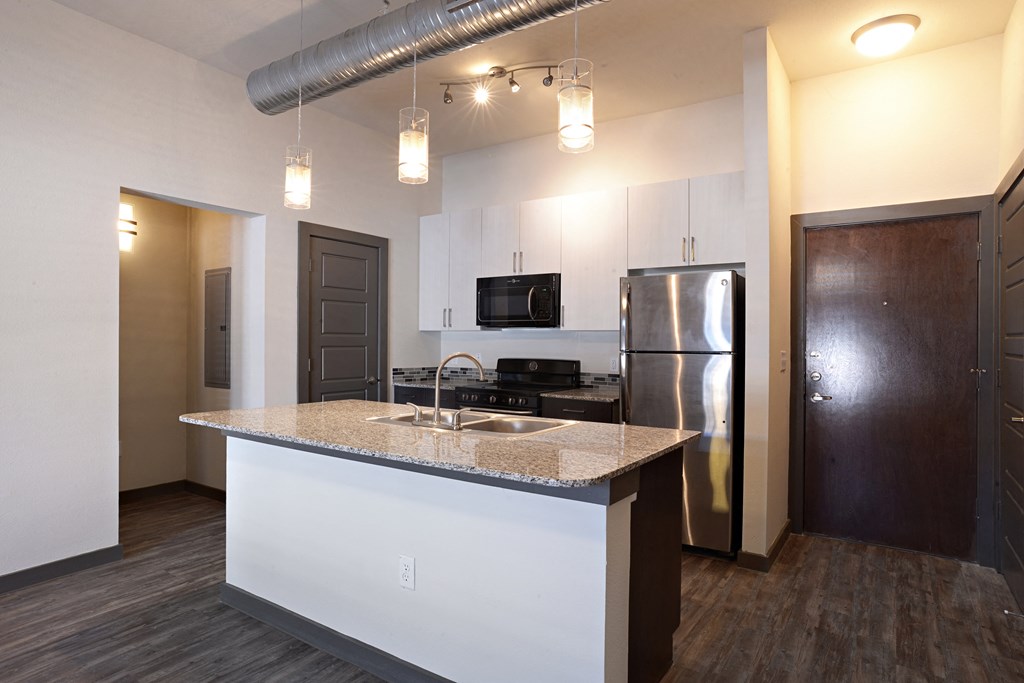 a kitchen with a granite counter top and a stainless steel refrigerator