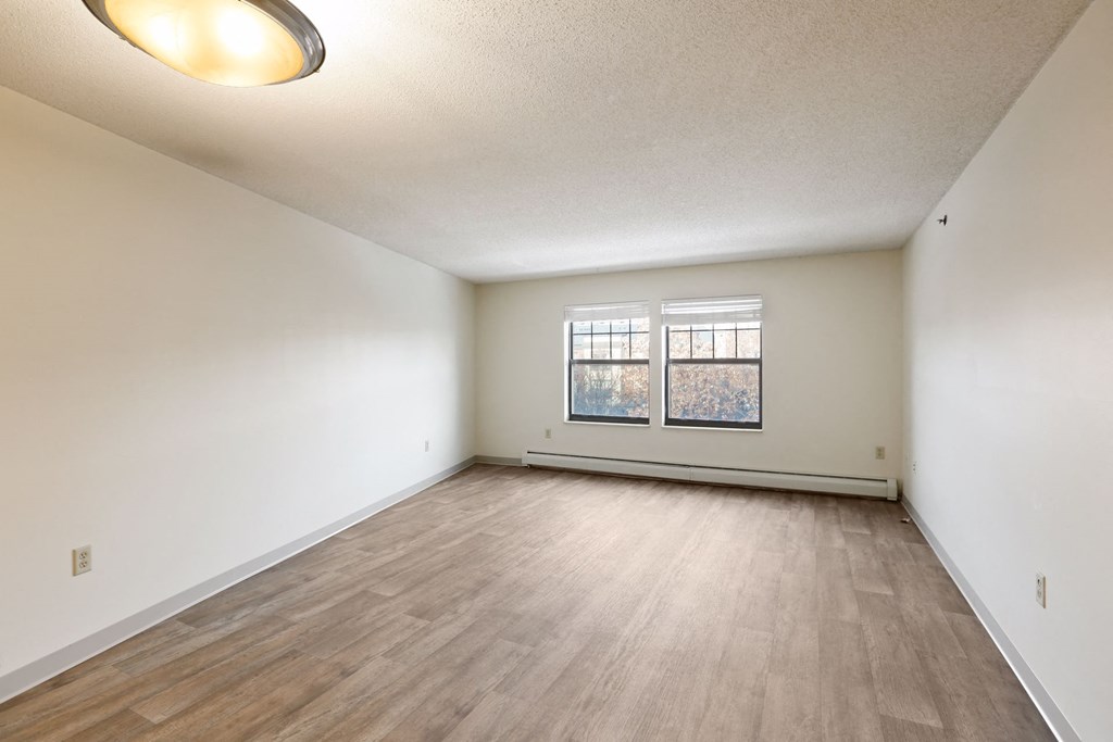 the living room and dining room of an empty home with wood flooring