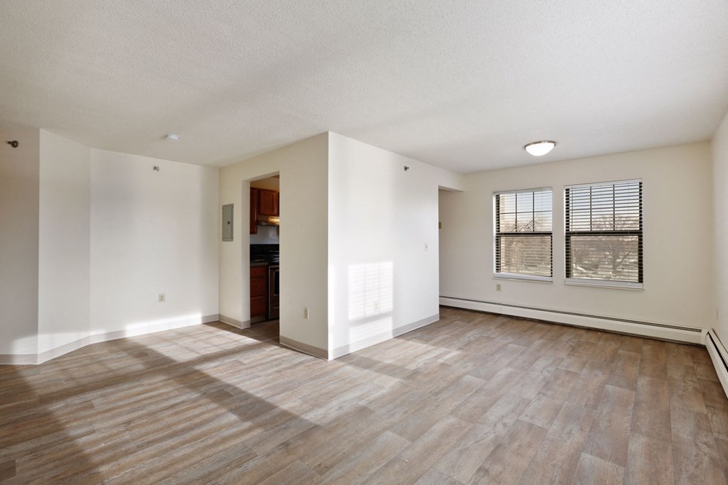 the living room and dining room of a new home with white walls and wood floors