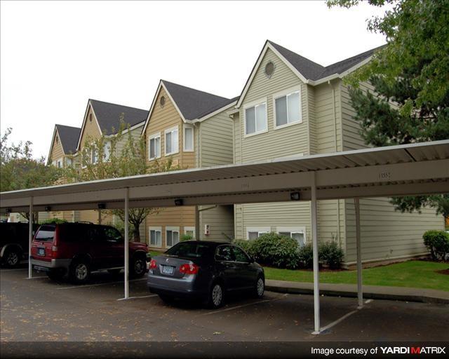 A carport with two cars parked in front of a house.