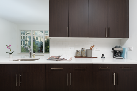 a kitchen with dark cabinets and a sink and a window