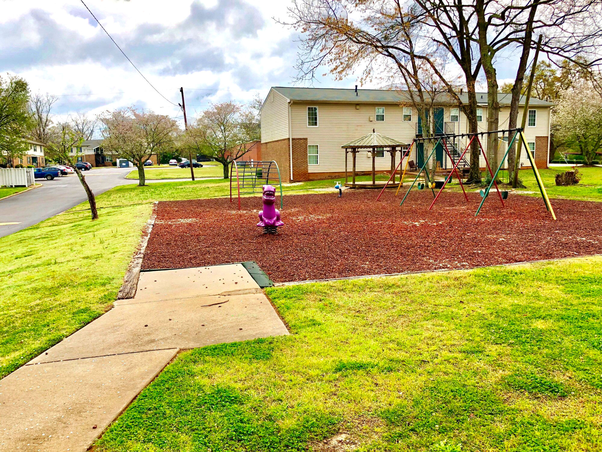 A playground with a red fire hydrant in the middle of a mulched area.