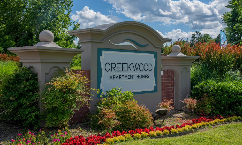 a sign for creekwood apartment homes in front of flowers