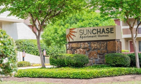 a sign for the sun chase apartment homes in front of trees and bushes