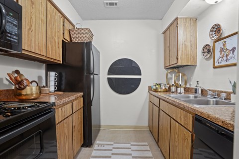 a kitchen with black appliances and wooden cabinets and a sink