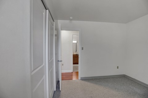 a bedroom with white walls and a door to a bathroom
