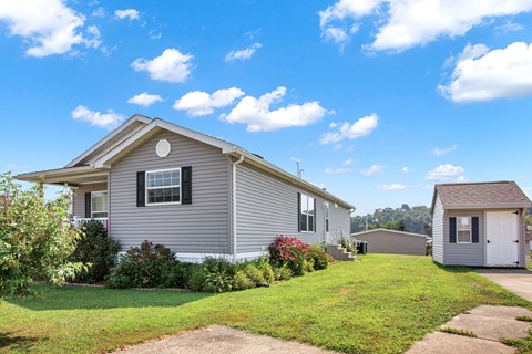 A house with a grey exterior and a small shed in the backyard.