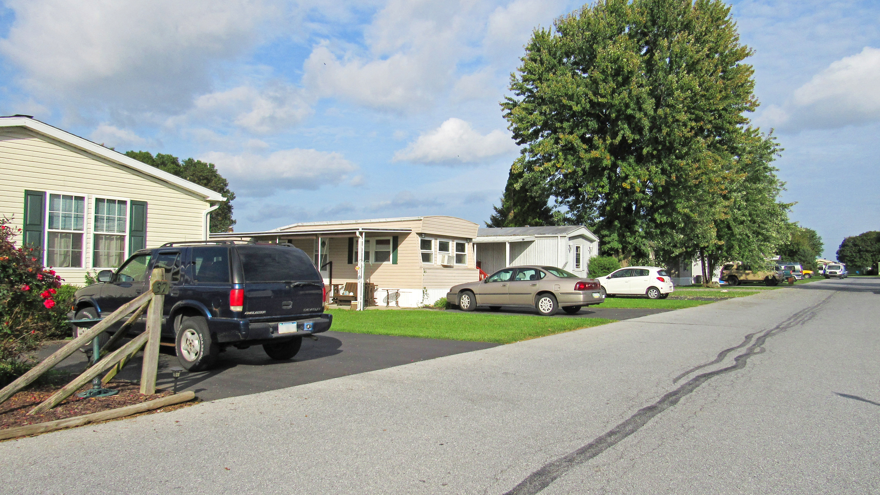 a row of mobile homes and cars parked in front of a street