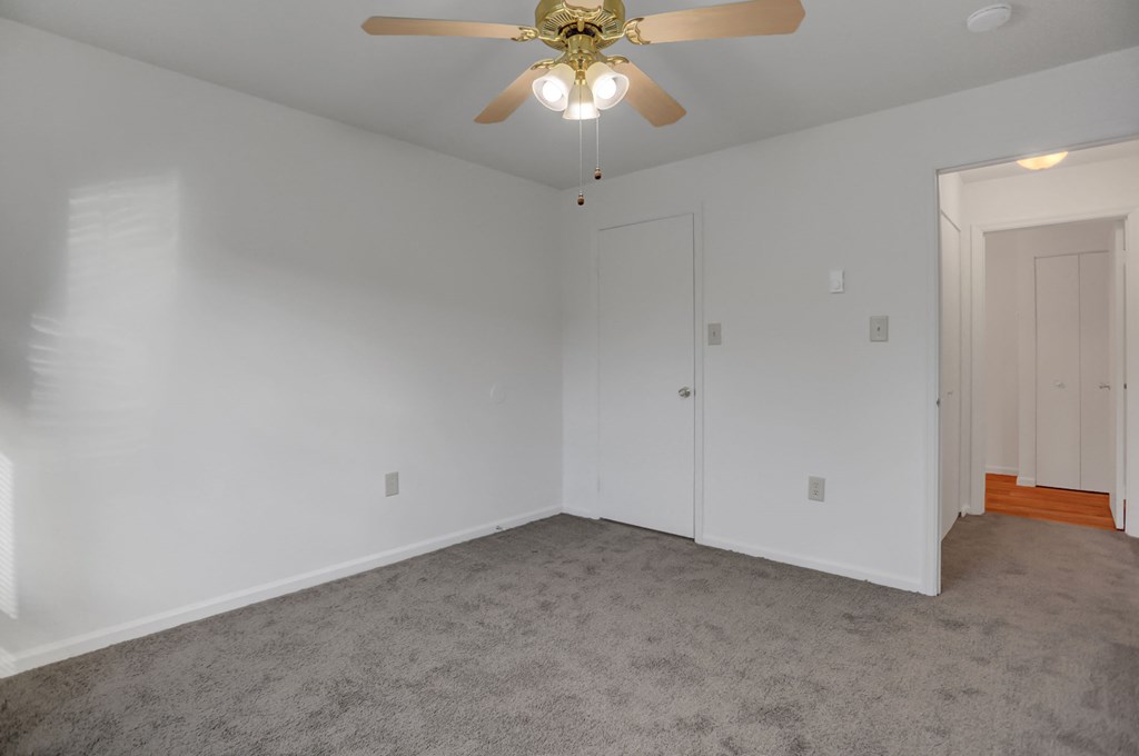 a bedroom with white walls and a ceiling fan
