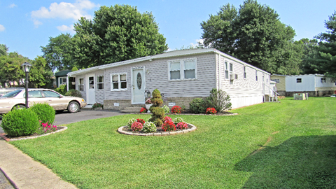 a white mobile home with a lawn and flower garden