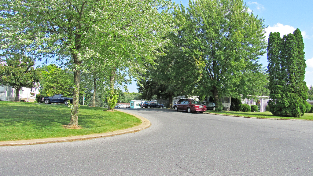 a street in a neighborhood with cars parked on the side of the road