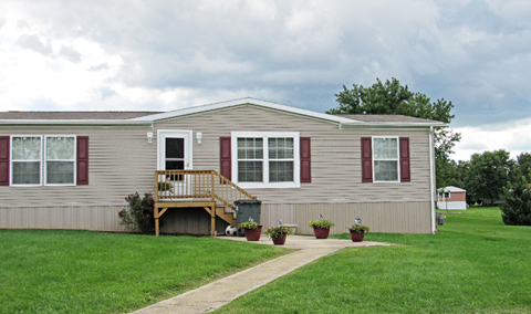 A house with a grey siding and red window frames.