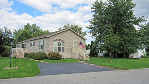 A house with a flag on it is surrounded by trees.