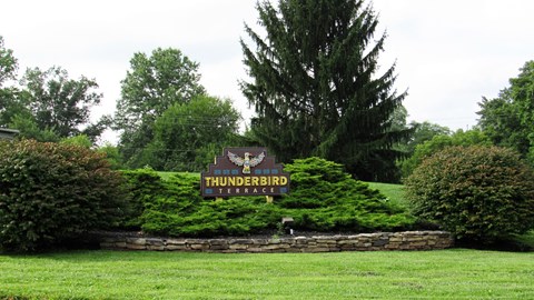 the sign for thunderbird estates sits in front of a green field and a tree
