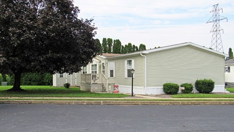 A house with a grey siding and a red and white sign on the front.