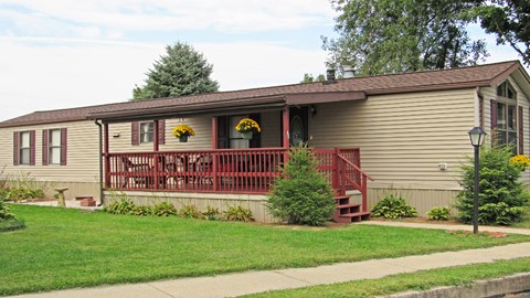 A house with a red railing and a tree in front.