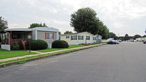 A street view of a residential area with houses and parked cars.