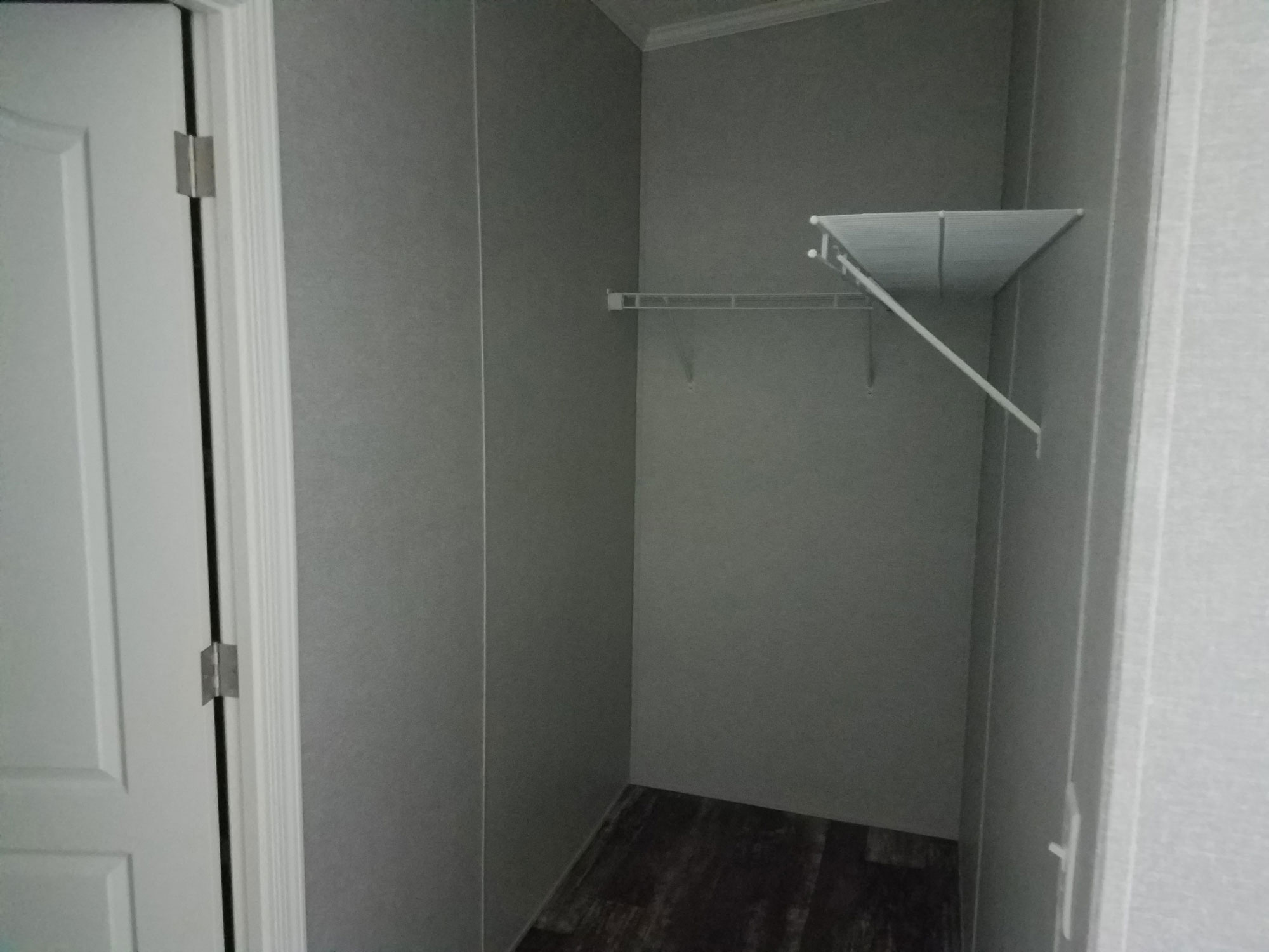 A white door is open to a small closet with a shelf.