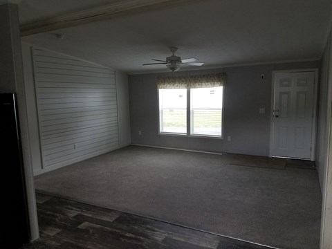 A room with a ceiling fan and sliding glass doors.
