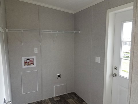 A room with a door, a window, and a wall with a few pictures and a shelf.