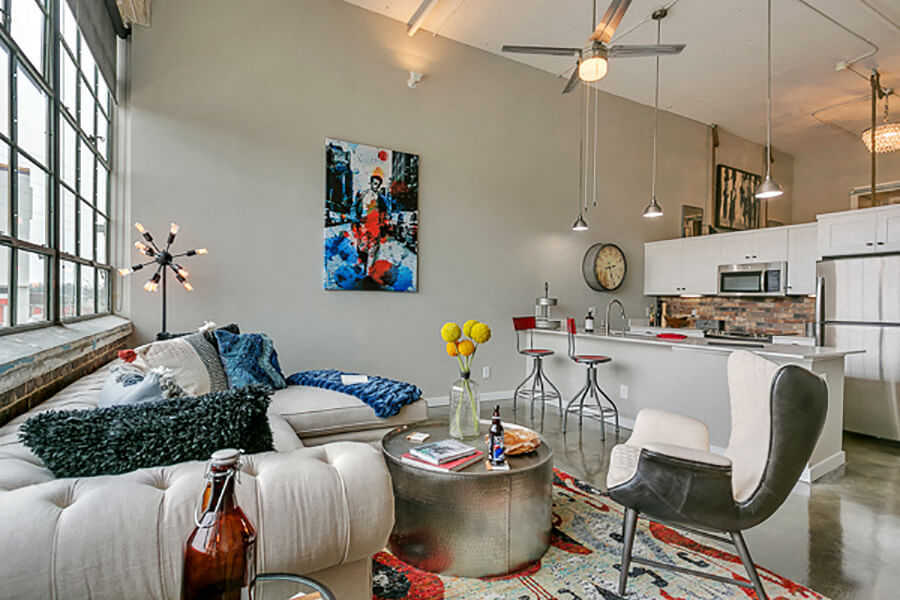 Living room with open concept kitchen, concrete floor, and beautiful white cabinets. Loft style apartment
