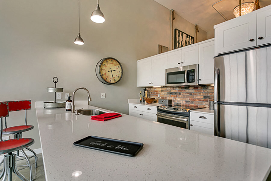 Modern kitchen with white cabinets and brick style backsplash, with white quartz countertop