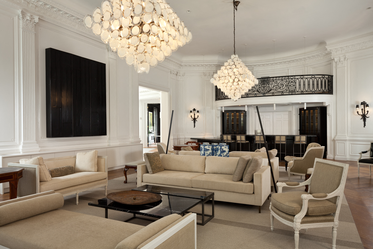 a living room with white walls and furniture and chandeliers