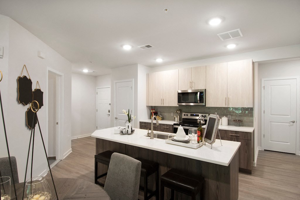 an open kitchen and dining area with a white counter top and a white kitchen island