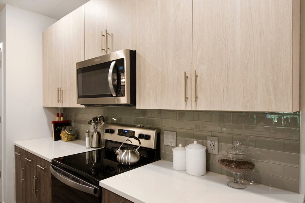 a kitchen with a stove and microwave and white counter tops