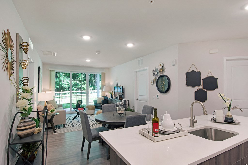 the living room and dining room of a home with a kitchen counter and a sink