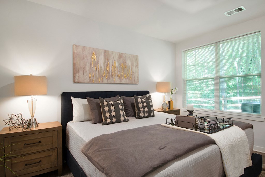 a bedroom with a large bed and two windows