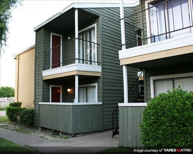 a green house with a balcony and a sidewalk