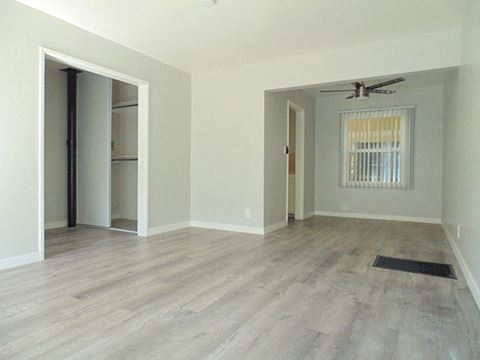 an empty living room with a hard wood floor and a closet